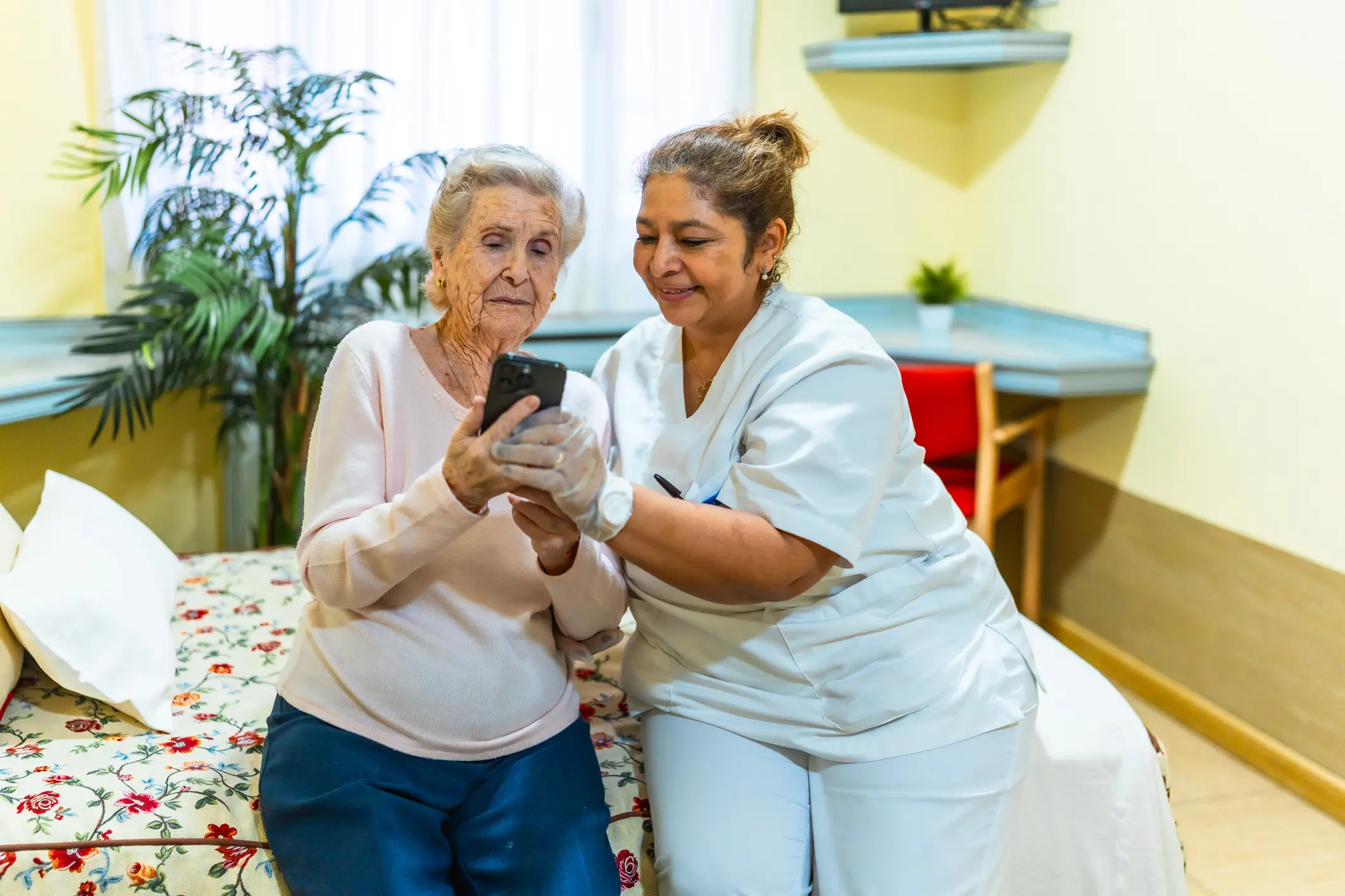 Elderly woman and nurse looking at phone.