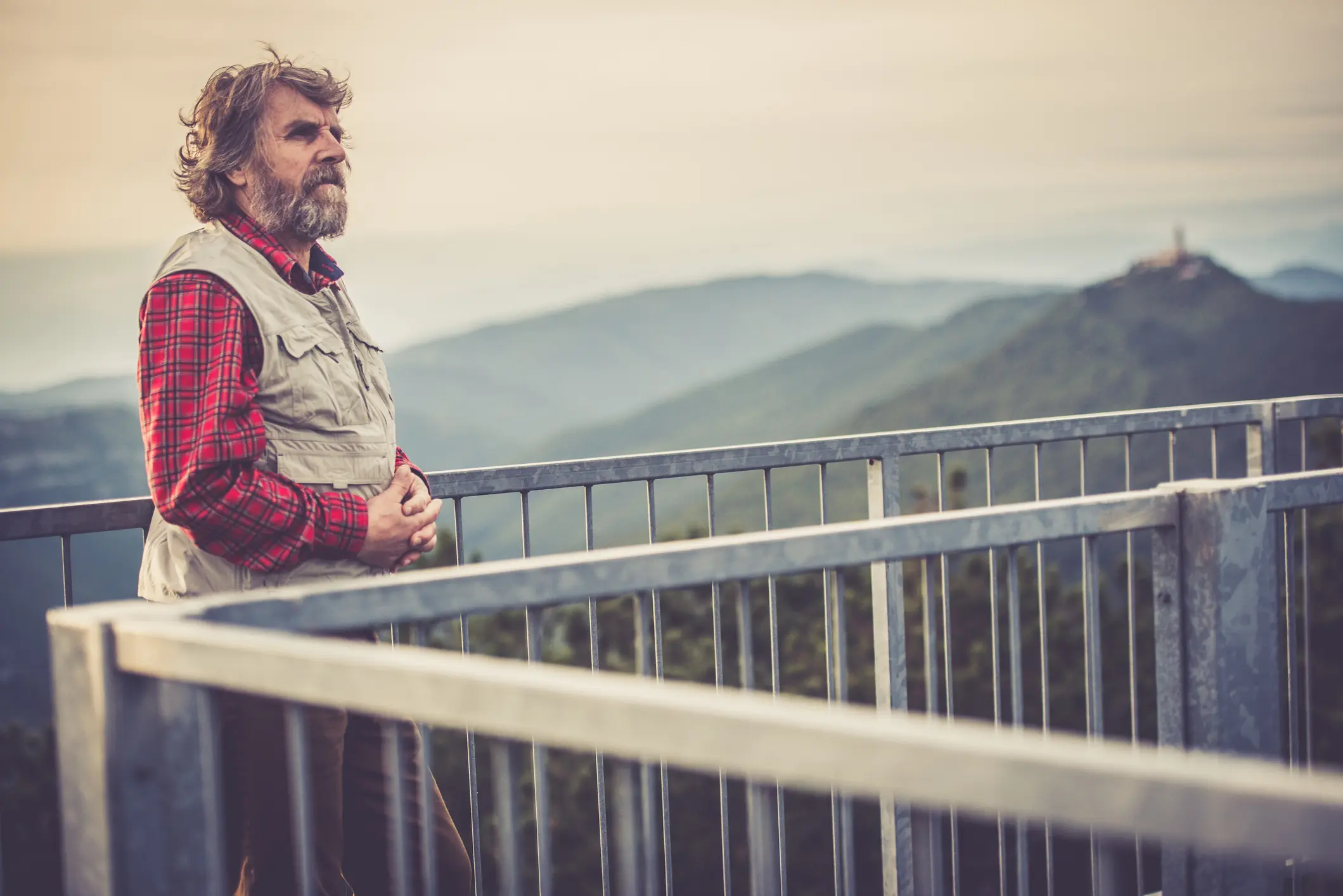 Man standing on balcony, scenic mountain view.