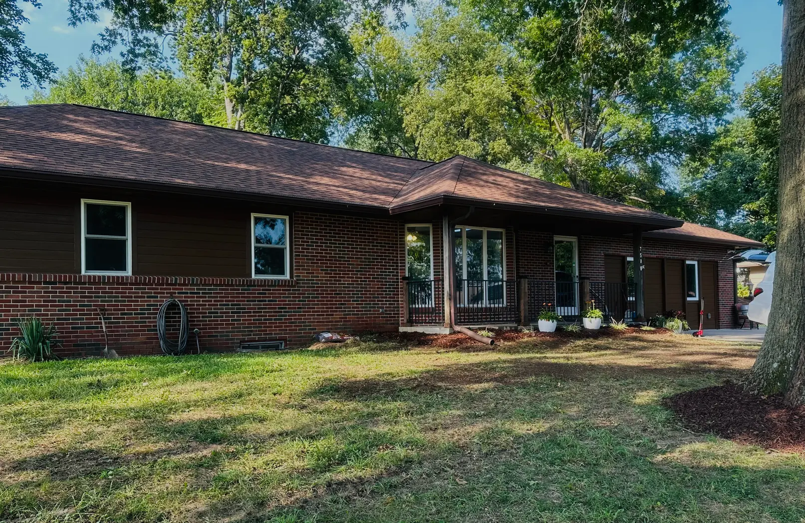 A cozy brick house with a spacious front yard and tall trees.