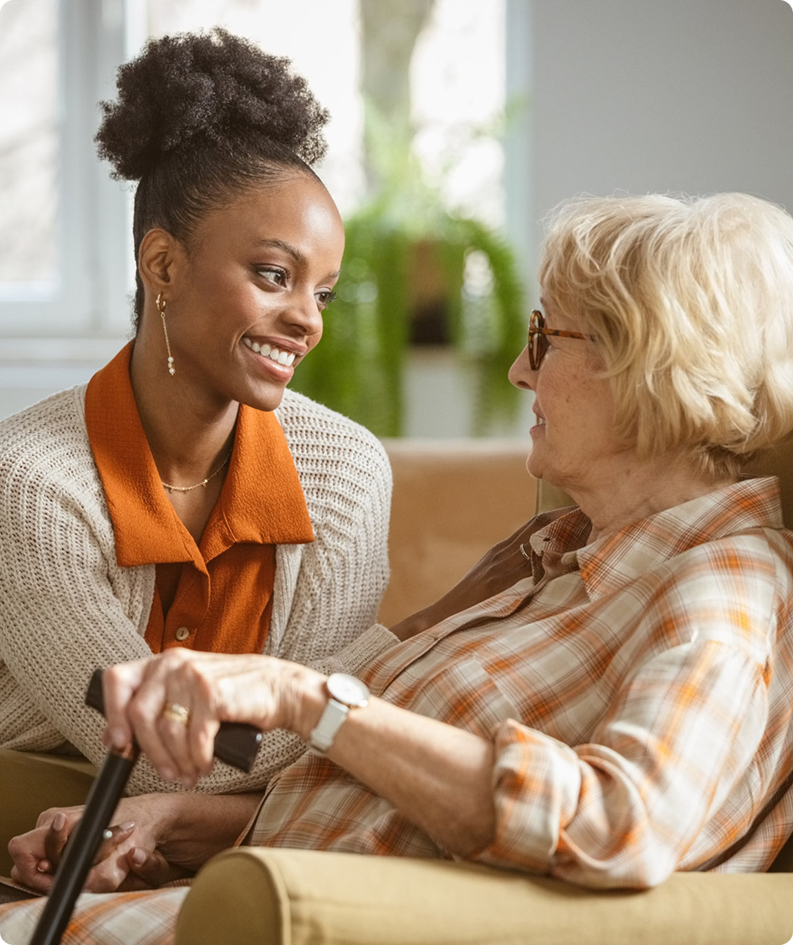 Young woman smiling at elderly woman indoors.