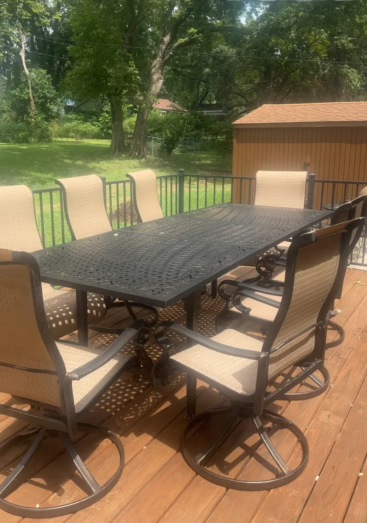 Outdoor patio dining set with cushioned chairs and a metal table on a wooden deck.