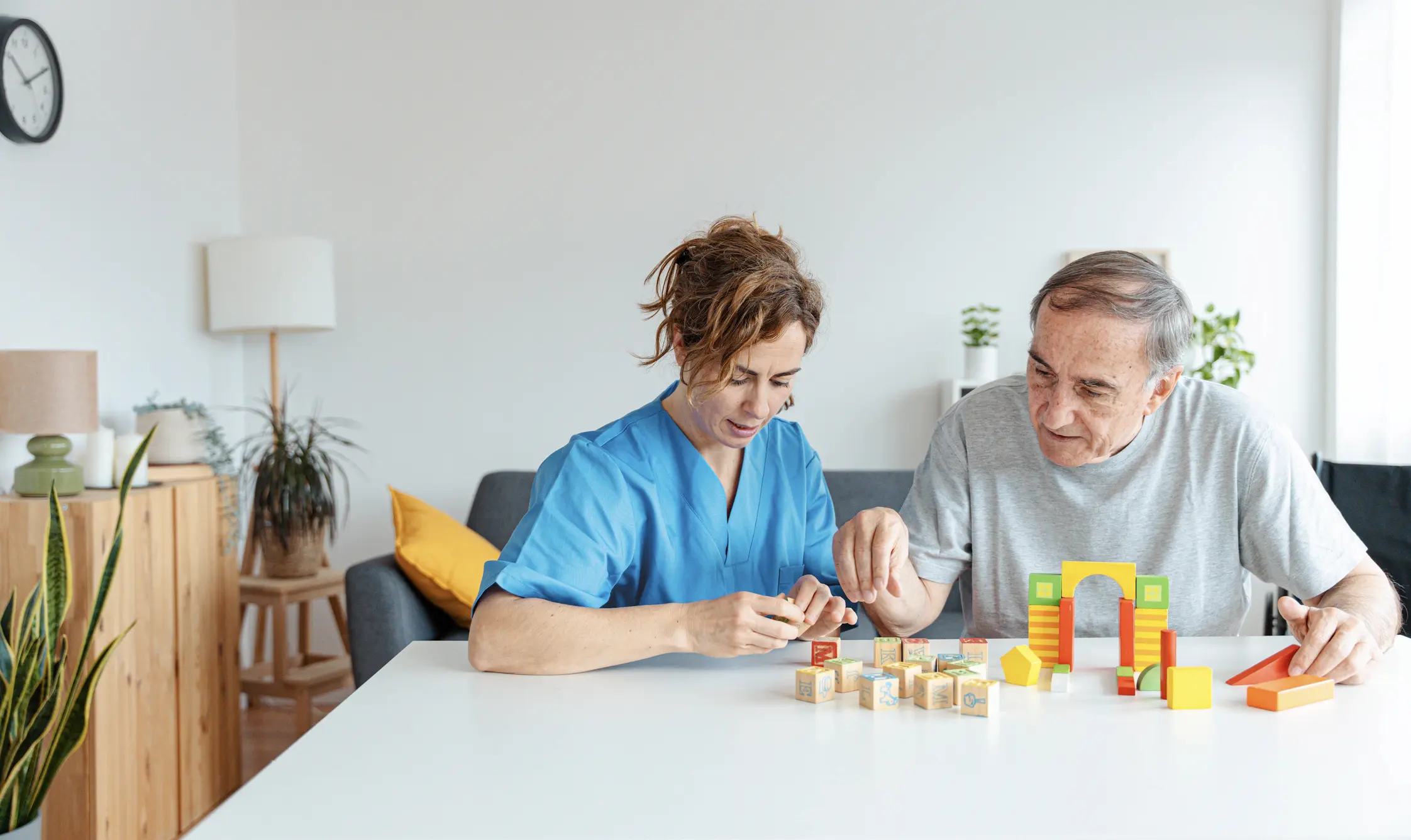 Caregiver and elderly man playing with blocks.