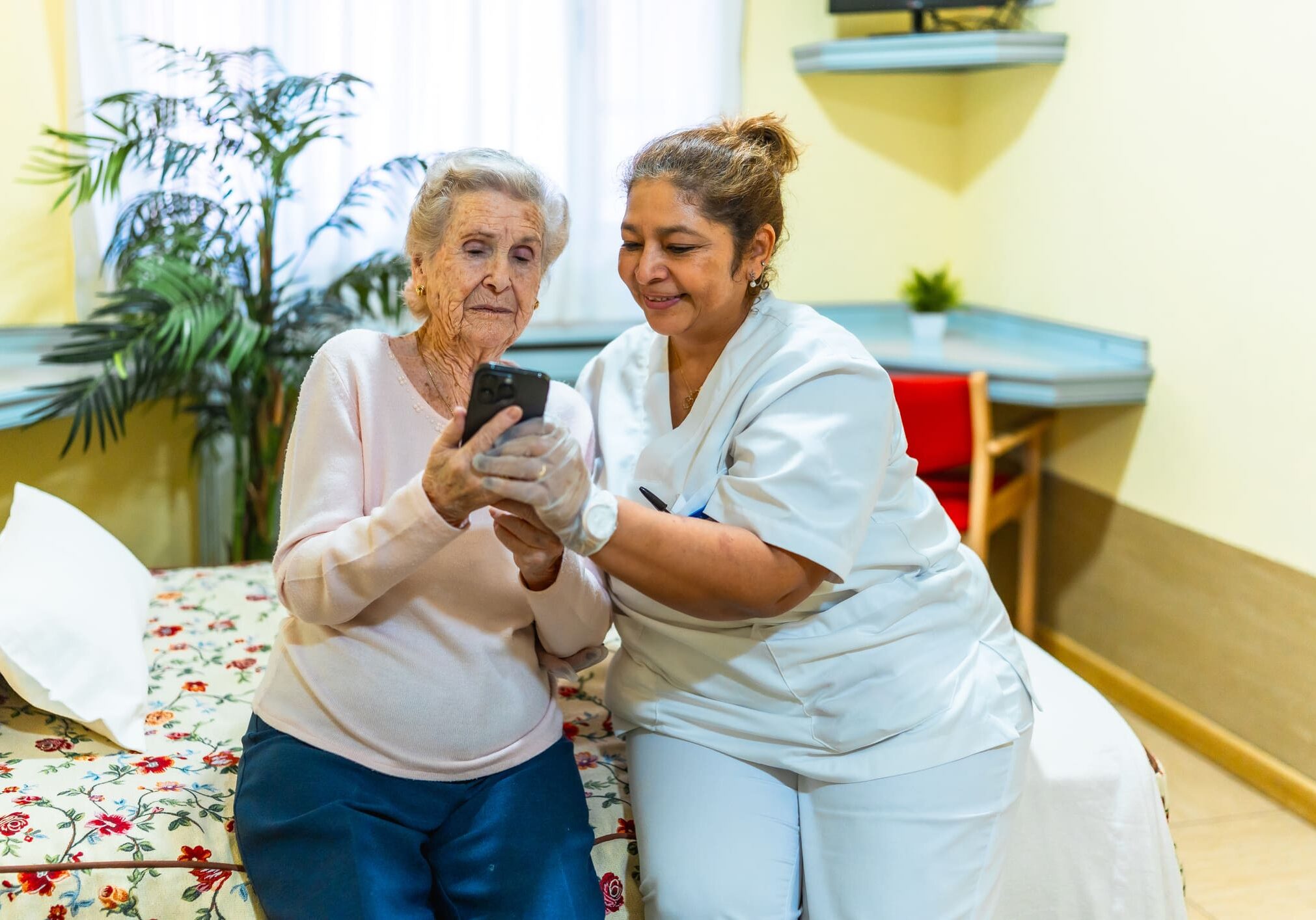 Elderly woman and nurse looking at phone.