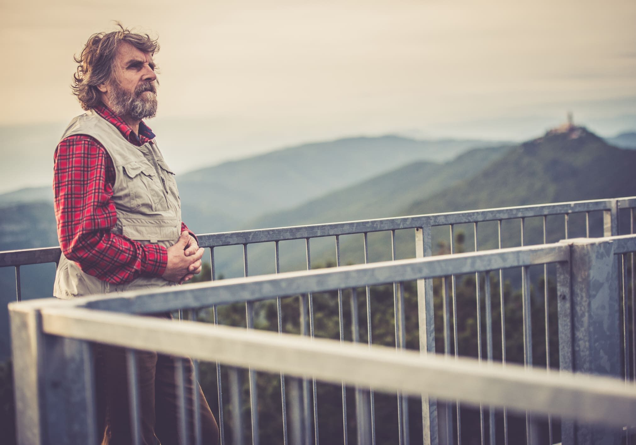 Man standing on balcony, scenic mountain view.